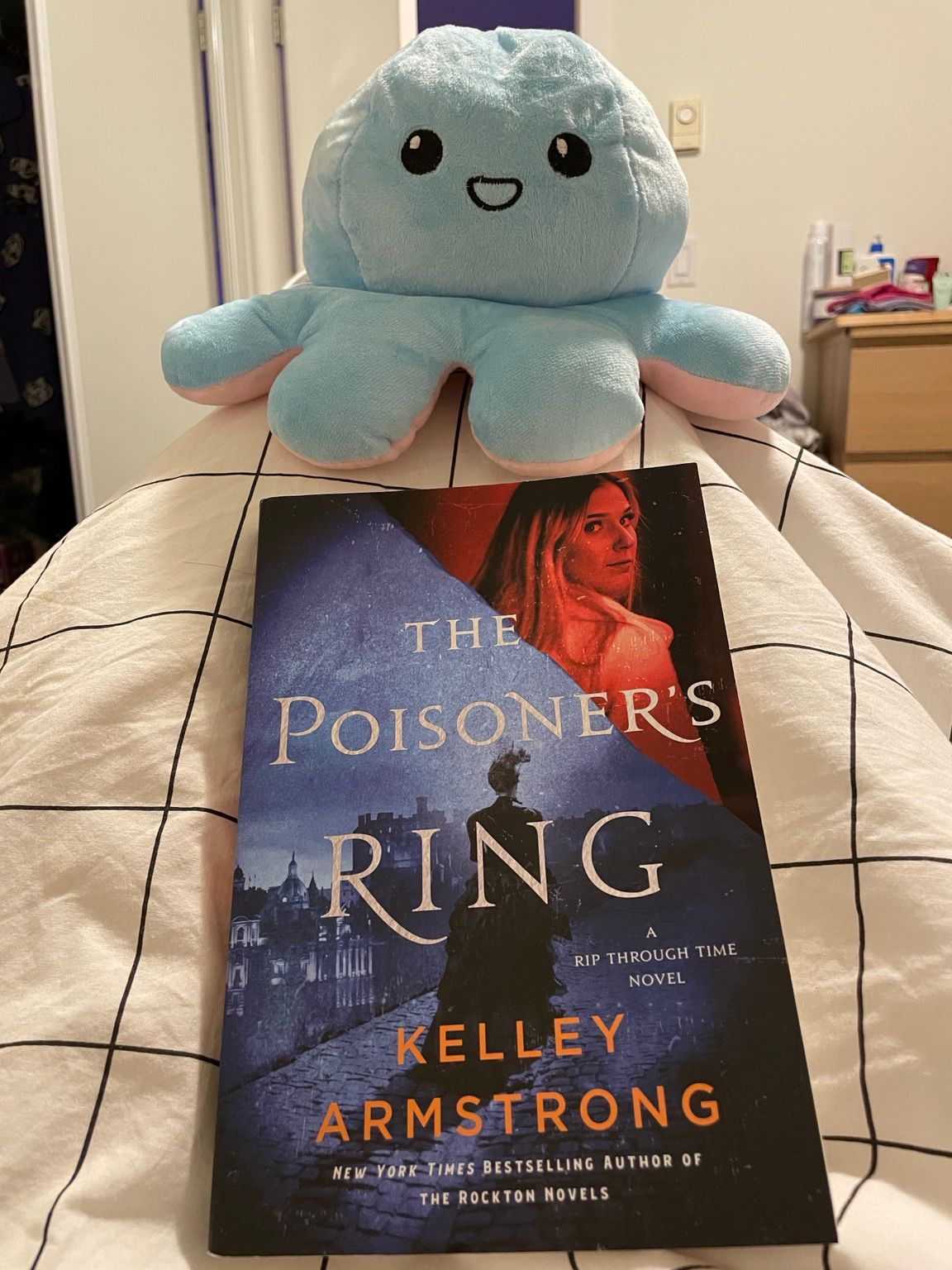 Photo spewing the paperback version of The Poisoner’s Ring, and a smiling octopus plushie